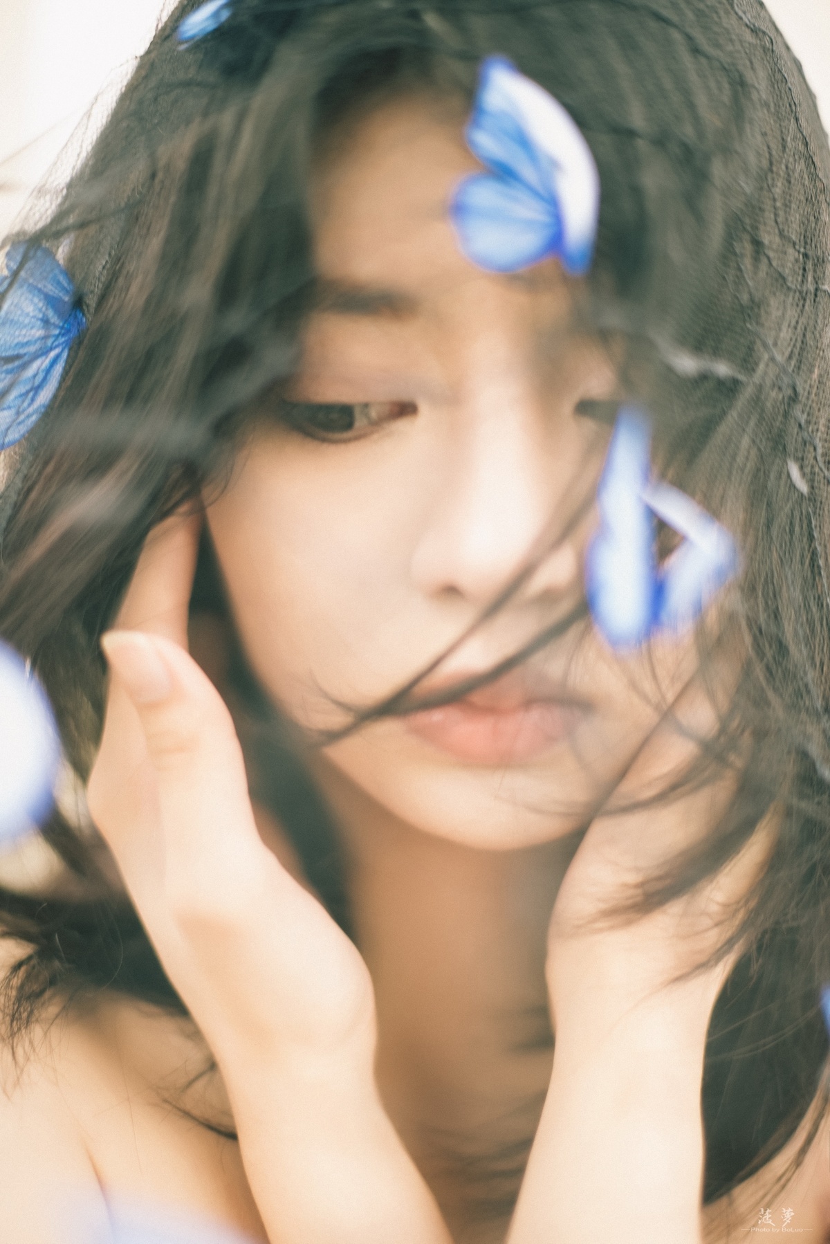一位年轻女子用手捂住脸庞 头上有朵蓝色花