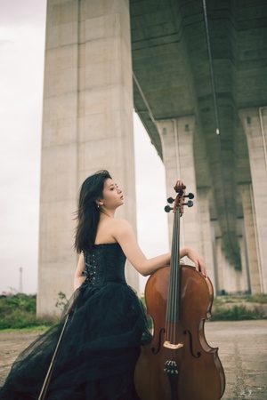 一位穿着黑色连衣裙的美丽女士在桥下演奏小提琴
