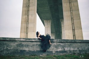 一张男子坐在桥边的照片