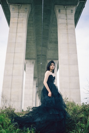 一个穿着黑色连衣裙的美女站在桥下