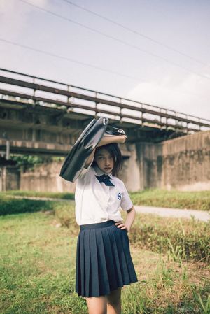 一位年轻女子穿着裙子 戴着帽子 在田野上举着一把伞
