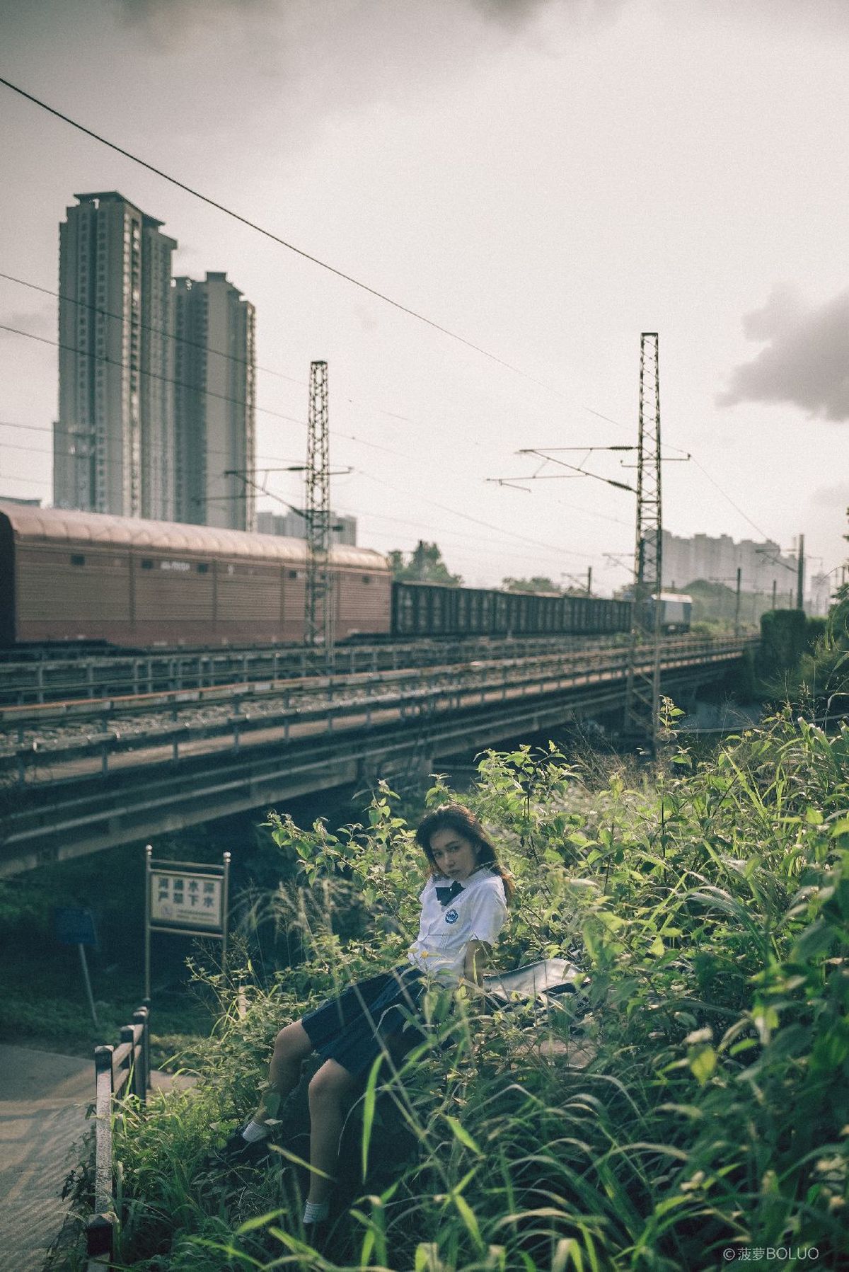一个年轻男子和女子坐在靠近铁路轨道的草地上 火车经过。