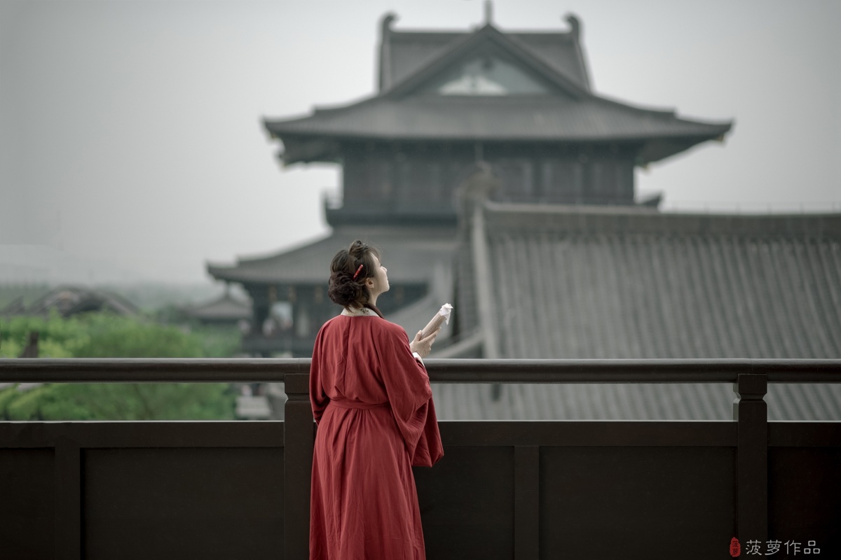 一位穿着红裙子的女人站在阳台上看着手机
