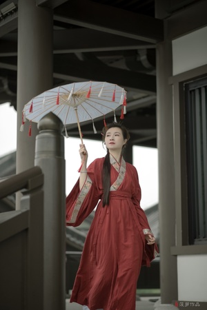 一位穿着传统红色裙子的年轻女子手持雨伞