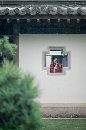 一位穿红衣服的女人正在窗口向外看一位在建筑物里的男人