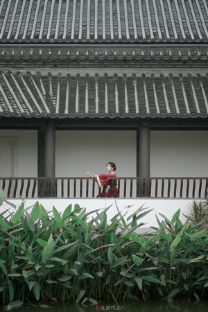 一位穿红衣服的女人站在一栋建筑物的阳台上