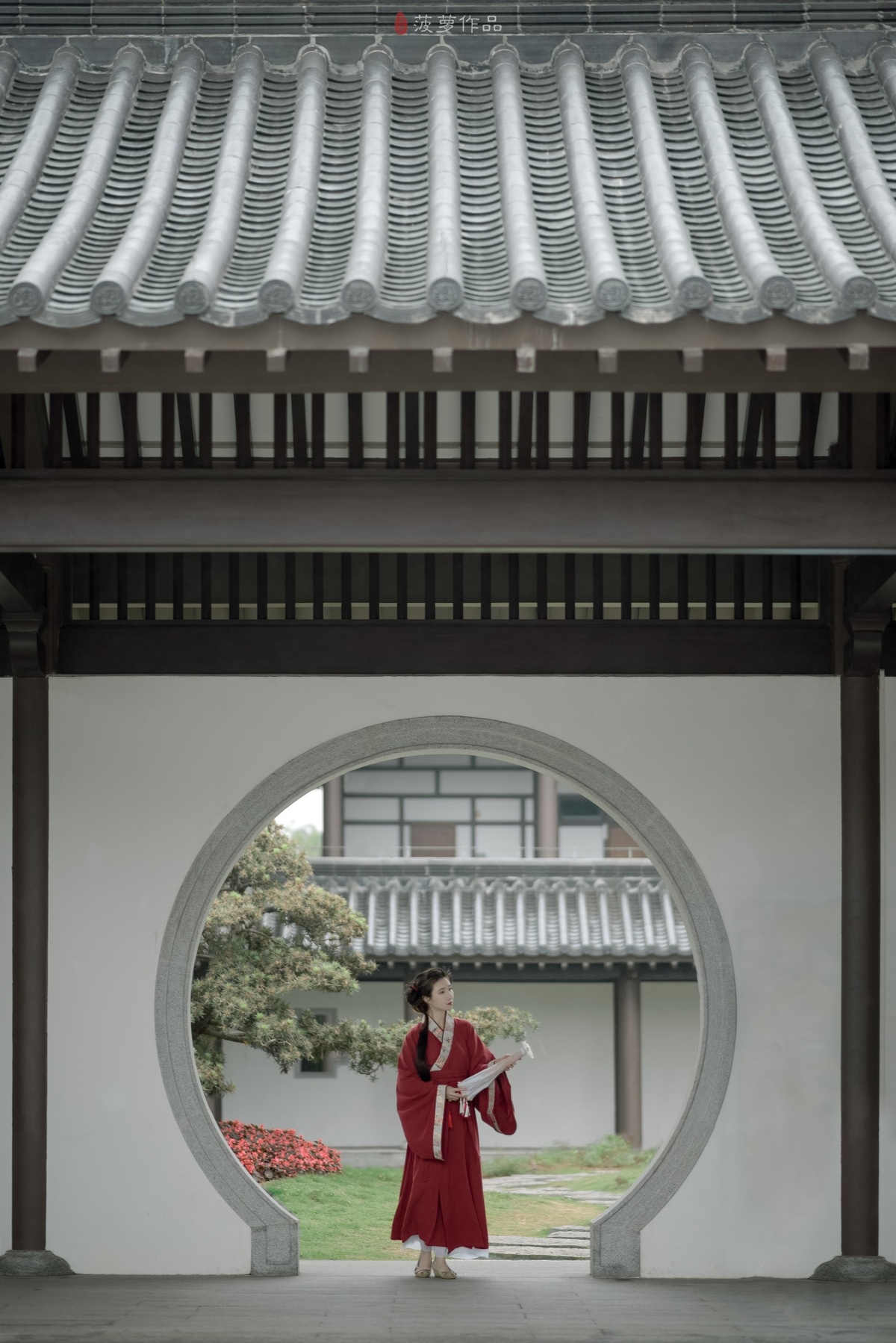 一位穿着红色连衣裙的女人穿过一座建筑物的拱门。