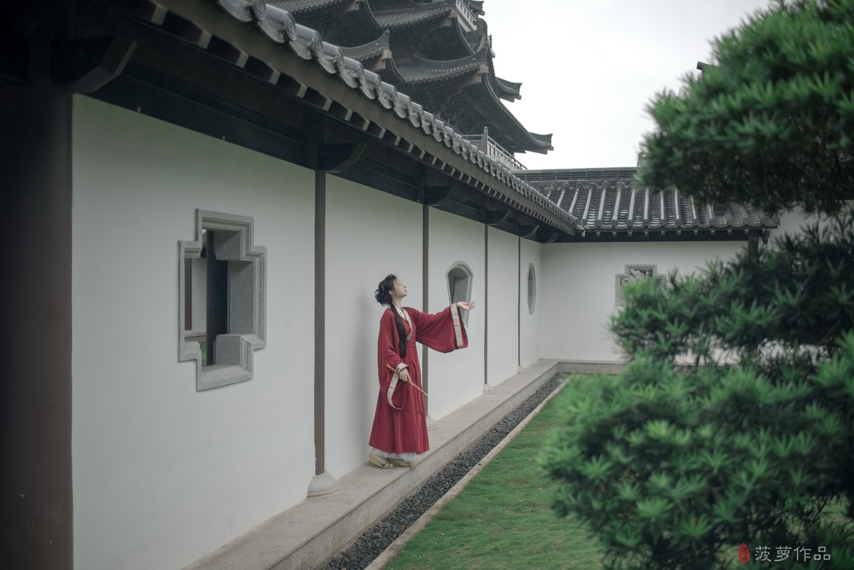 一位穿着红色连衣裙的女孩走在有着白色墙壁的传统中式房屋的庭院中
