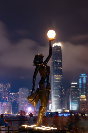 夜晚摩天大楼的天际线前 一个雕塑手持一盏灯