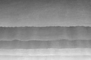 一张黑白照片 展示了一块冲浪板在水面上 天空中有一排波浪。