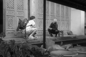 一张黑白照片 一对男女坐在老建筑前的一张长凳上。