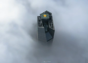 云雾缭绕的天空下 有一座带钟楼的塔楼。
