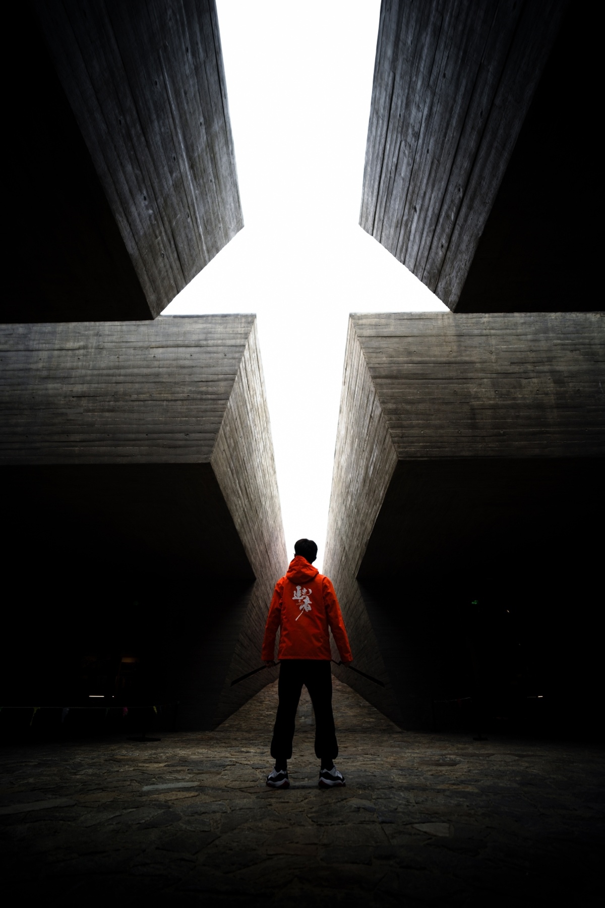 一个穿红夹克的男人站在一个黑暗的隧道里 带着滑板。