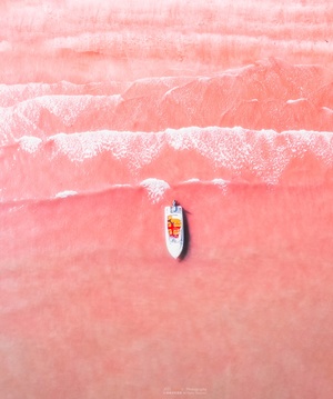 一艘小船漂浮在粉红色沙子上