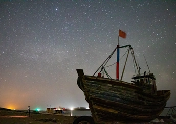 夜晚海滩边的老船 天空中繁星闪烁