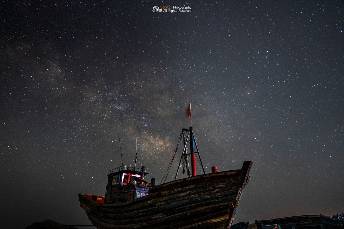 夜晚星空下的一艘老船 天空中挂着银河系。