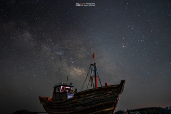 夜晚星空下的一艘老船 天空中挂着银河系。