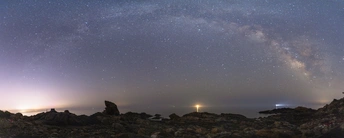 一座岩石突起上的灯塔 夜晚被星空照亮。