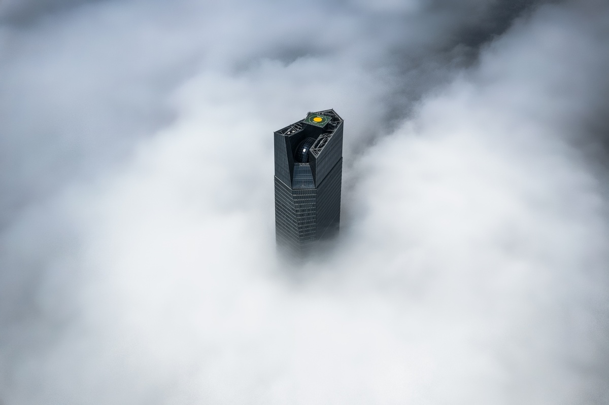 雾气缭绕的云层中 一座高楼的顶部照片
