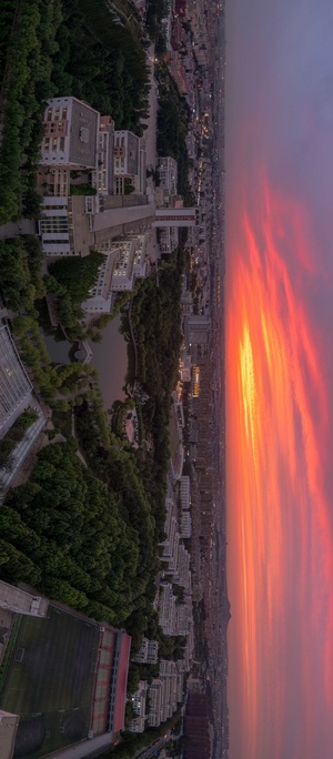 夕阳下城市的 aerial view 天空中飘着红云。