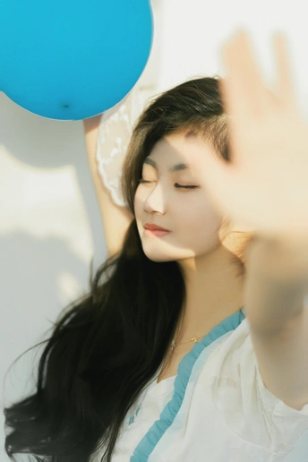 一个年轻的女人把一个蓝色的气球举在脸前