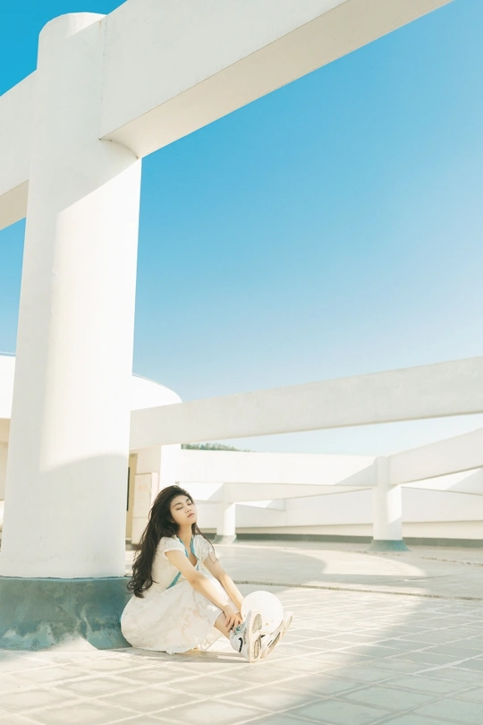 一个穿着白色连衣裙的年轻女子坐在一只白猫旁边