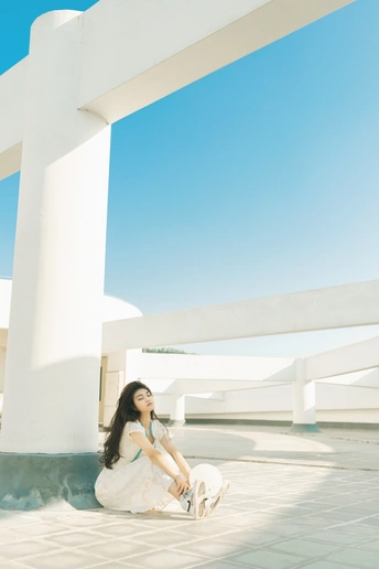 一个穿着白色连衣裙的年轻女子坐在一只白猫旁边