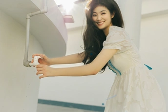 一张身穿白色连衣裙的年轻女子对着镜头微笑的照片