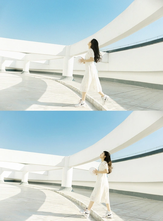 一个穿着白色连衣裙的女人站在一栋白色建筑前