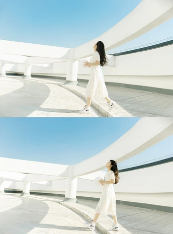 一个穿着白色连衣裙的女人站在一栋白色建筑前