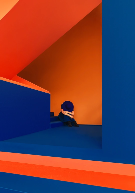 一个人坐在彩色房间的一个平台上 这个房间有橙色和红色的墙壁。