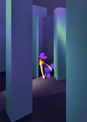 一个戴紫色帽子的女人坐在一个蓝色椅子上 在一个有紫色墙壁的房间里。