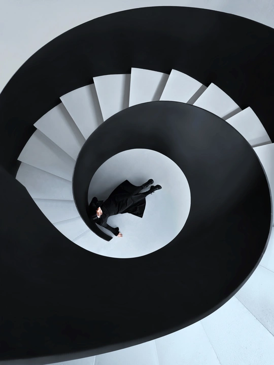 一个穿黑色西装的男人站在螺旋楼梯的顶部