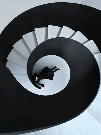 一个穿黑色西装的男人站在螺旋楼梯的顶部