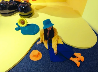 一位戴蓝帽子的女人坐在玩具旁边地上