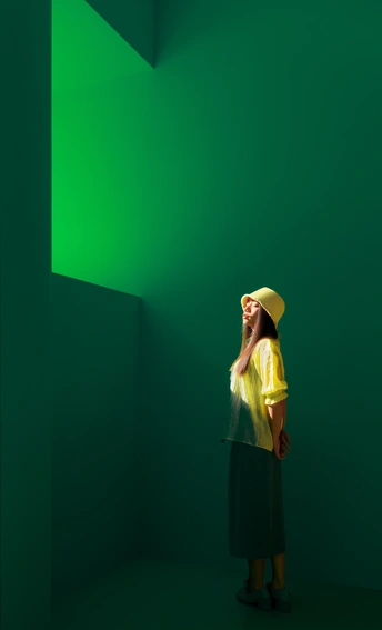 一位穿着黄色衬衫和帽子的人在绿色房间里打电话