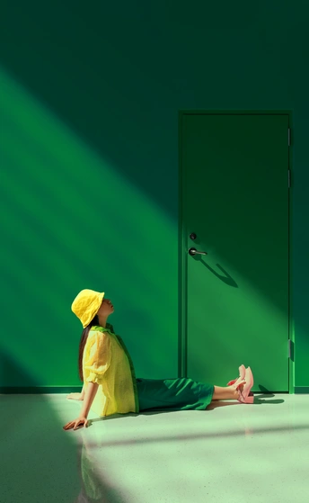 一个穿着黄色雨衣的年轻女子坐在一个绿色墙壁和绿色门的房间里