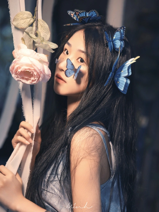 一位年轻女子头戴粉色玫瑰 发间有一只蓝色的蝴蝶。