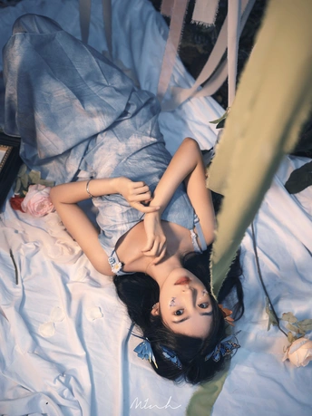 一个年轻女子躺在床上 她身边有一个洋娃娃。