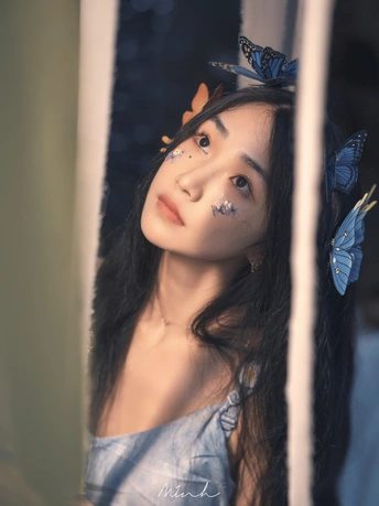 一位长着蓝眼睛 脸上有一只蝴蝶做装饰的年轻女子在镜子里被反射出来。