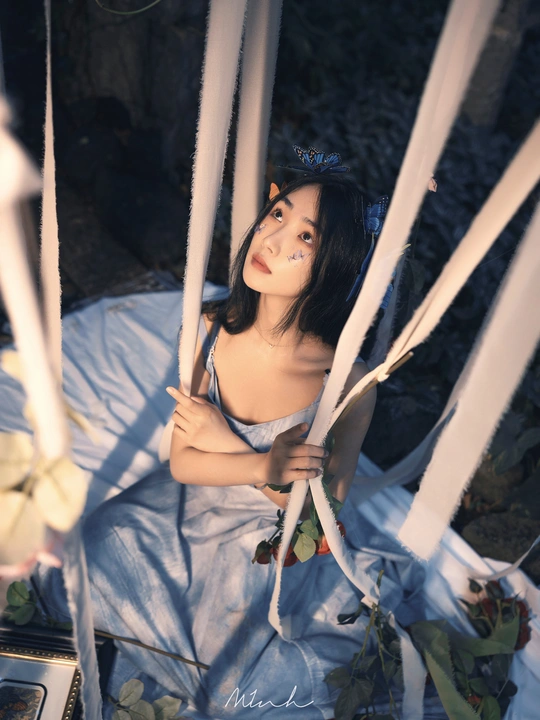 一个穿着蓝色连衣裙的年轻女子坐在一个白色秋千上