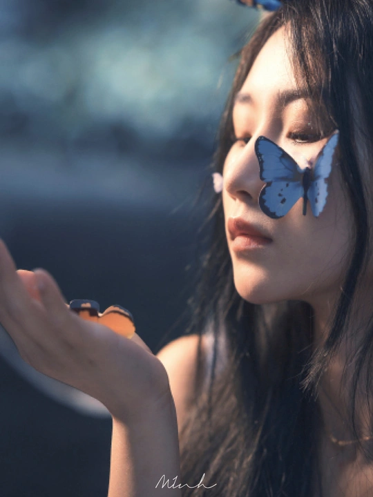 一位年轻女子脸上贴着一只蓝色的蝴蝶 手里拿着一部手机。