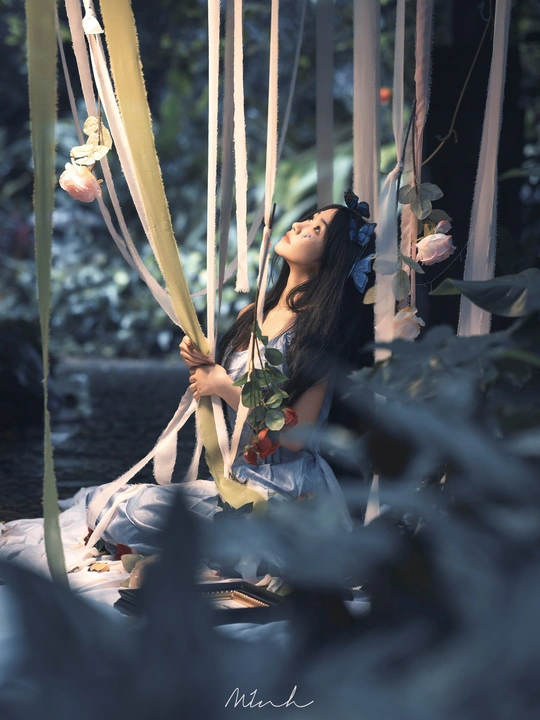 一位年轻女子坐在从树上挂着的秋千上。