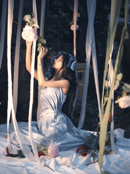 一个穿着白色连衣裙的年轻女子抱着玫瑰坐在林中的秋千上