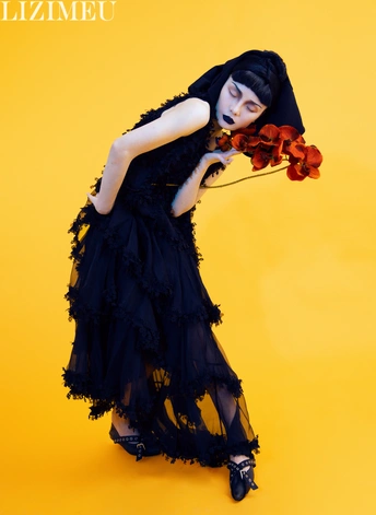 一个穿着黑色衣服的年轻女子抱着一把小提琴和花。