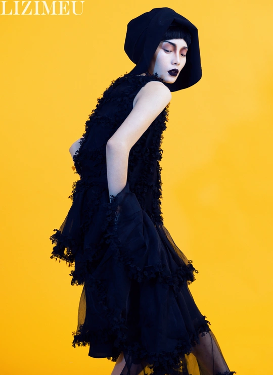 一位穿着黑色连衣裙和黑色帽子 背景为黄色 的人物模型