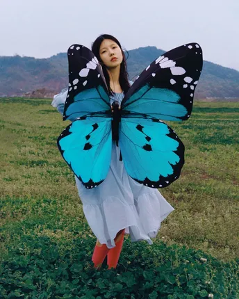 一位拥有蓝色翅膀的美丽女人在田野中