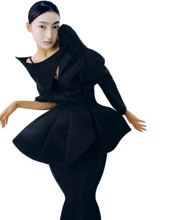 一位穿着黑色连衣裙的模特儿摆出像现代舞者的姿势。