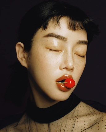 一个涂着黑色妆容 闭着眼睛 嘴唇上涂着红色口红的年轻女子