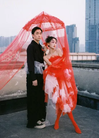 一位穿着红裙子的女人站在一位男士旁边